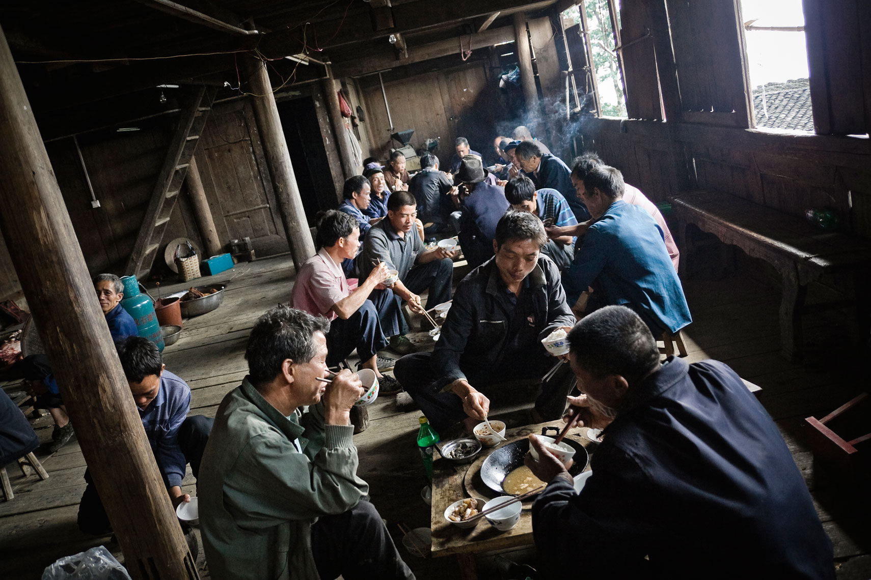 CHINA. Guangxi Province, September 2012. Zhongliu village. Men of the village have a lunch break during the construction of a traditional wood house.